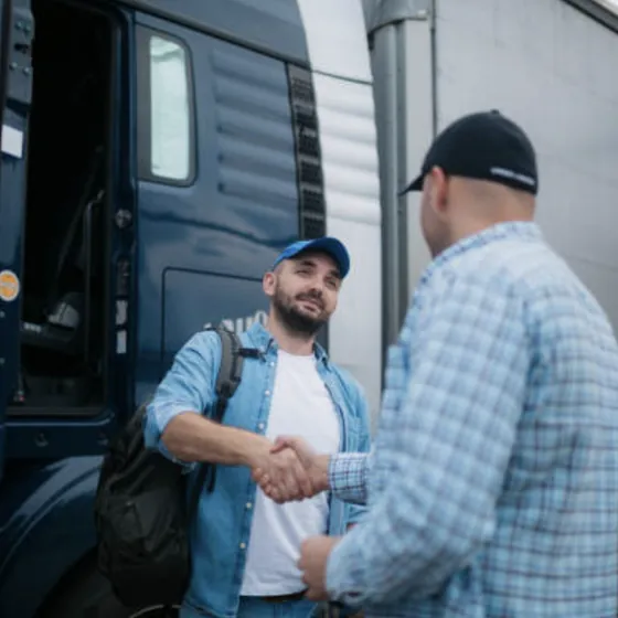 Two men shaking hands beside a truck